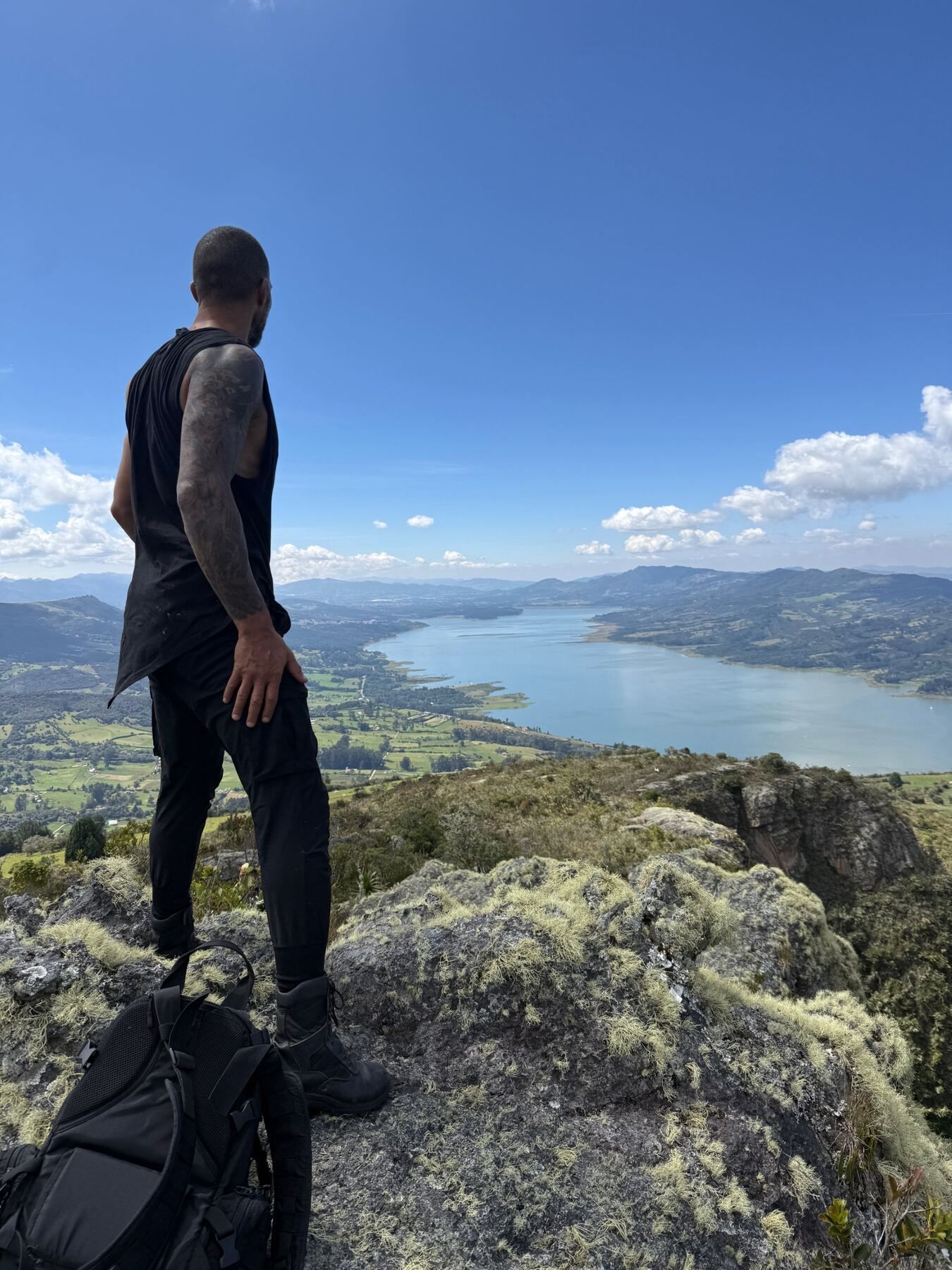 Alain standing on a rocky summit, looking out over the mountains and the long lake below